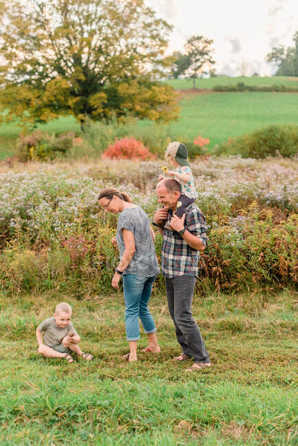 Two little kids and their grandparents on a walk in a flowery meadow — Stock Photo