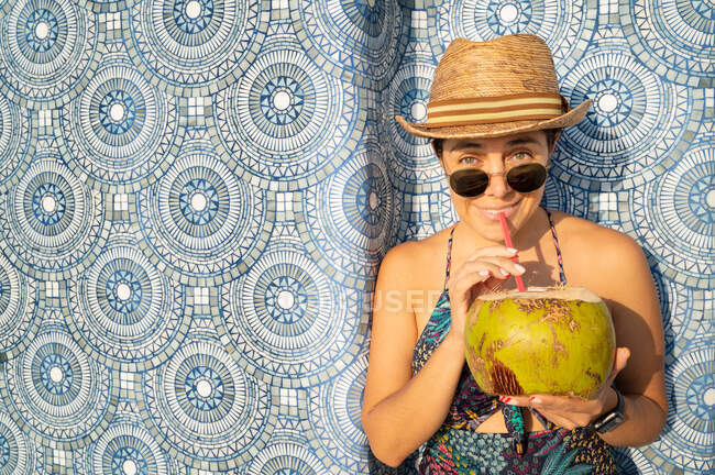 Mulher feliz relaxar na piscina e beber água de coco. — Fotografia de Stock