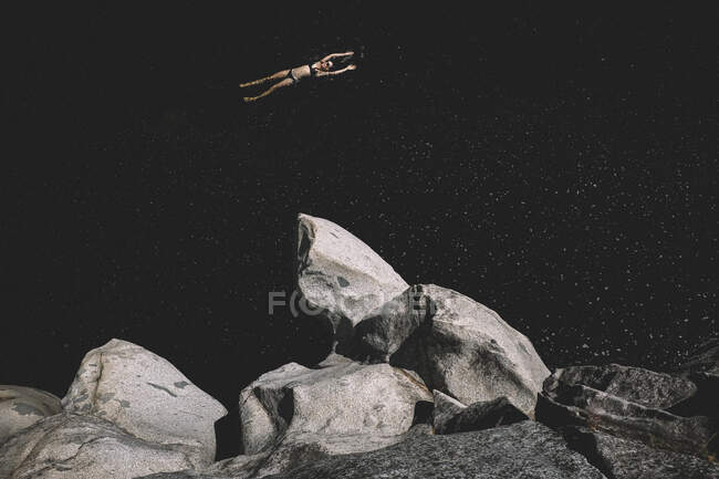 Femme flotte bras tendus dans une piscine d'eau sombre. On dirait Space. — Photo de stock