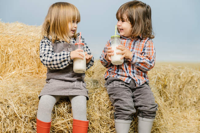 Cute little girls on a haystack with milk — Stock Photo