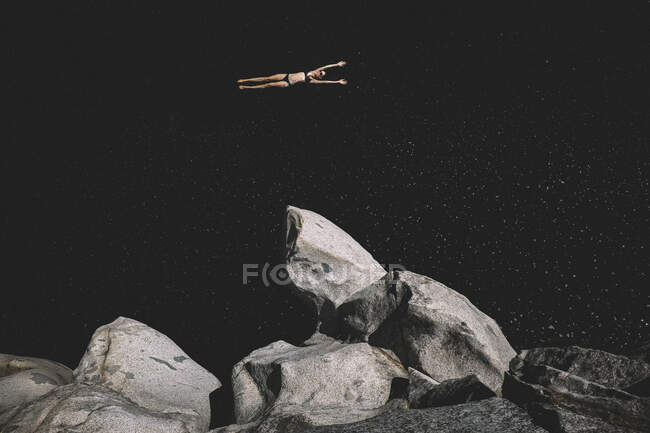 Donna galleggia braccia estese in una pozza d'acqua buia. Sembra lo spazio. — Foto stock