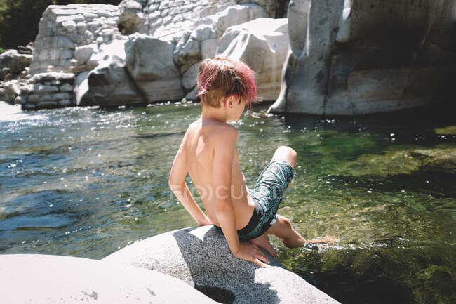 Menino com cabelo rosa mergulha um dedo do pé no rio — Fotografia de Stock