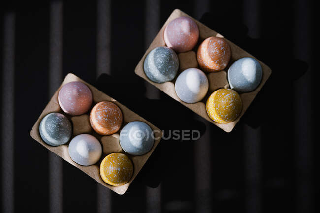Високий кут барвистих Великодніх яєць у яєчній коробці на чорному тлі. — стокове фото