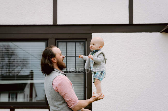 Веселый папа играет с маленьким сыном на переднем дворе весной — стоковое фото