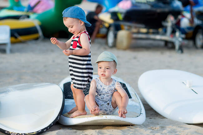 Hermanos gemelos en traje de verano jugando en una tabla en el campamento de windsurf - foto de stock