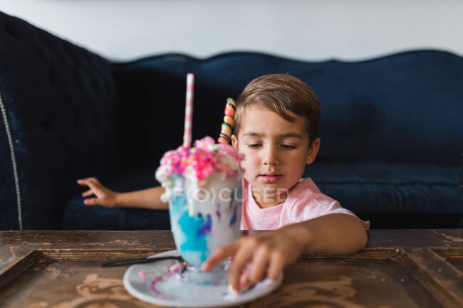 Little boy eating ice cream in the kitchen — Stock Photo