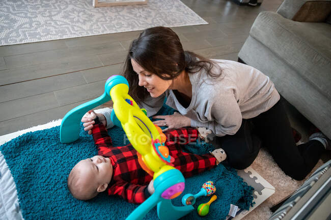 Mãe brincando com o bebê na sala de estar. — Fotografia de Stock