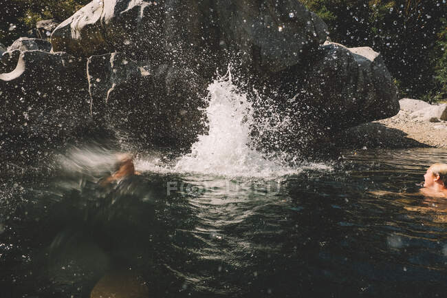 Большие брызги и вода из мальчишек прыгают в прорубь — стоковое фото