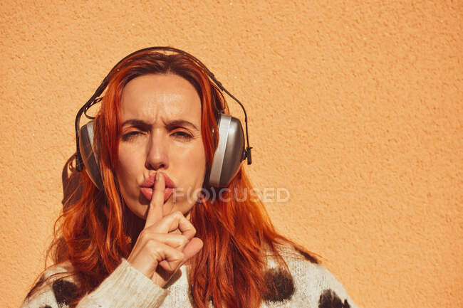 Bianca donna caucasica con caschi per proteggersi dal rumore chiede silenzio. Concetto di non fare rumore. — Foto stock