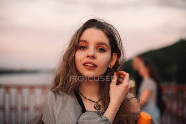 Портрет дівчини - підлітка, що стоїть на мості на заході сонця влітку. — стокове фото