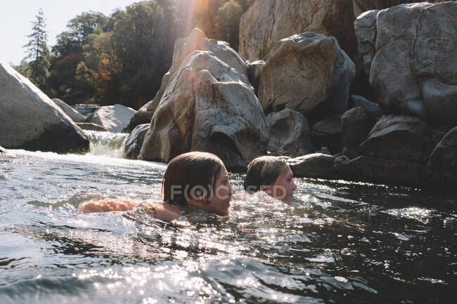 Друзья плавают вместе рядом с водопадом в реке Юба — стоковое фото