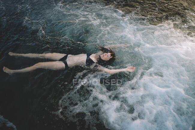 Woman Floating in a Dark Pool in the Early Morning Light — Stock Photo