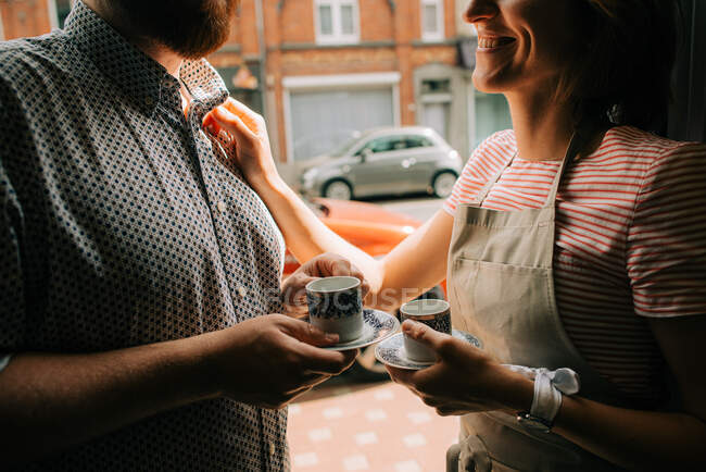 Young couple with cups of coffee smiling to each other in the street — Stock Photo