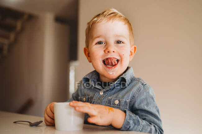 Adorabile ragazzo bianco con i baffi di latte sorridente con la lingua fuori — Foto stock