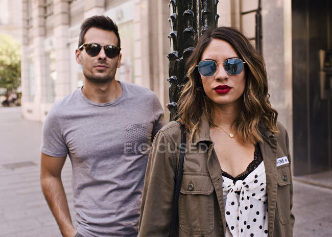 Couple of boyfriend and girlfriend wearing sunglasses on a city — Stock Photo