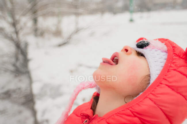 Child catching snowflakes on tongue in blizzard — Stock Photo