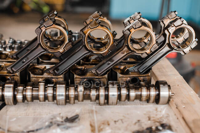 View of shiny pistons on a wooden surface in a garage and cam shaft — Stock Photo