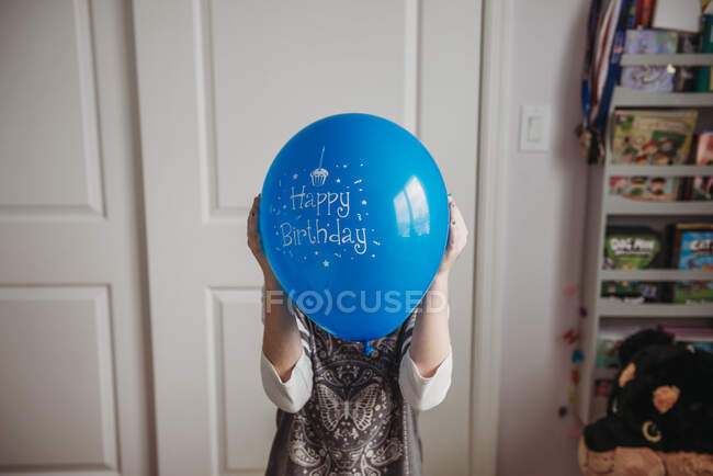 Tween girl holding blue birthday balloon in front of face — Stock Photo