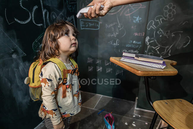 Der Lehrer nimmt die Temperatur eines Kindes zum Zeitpunkt seines Eintritts in den Unterricht — Stockfoto