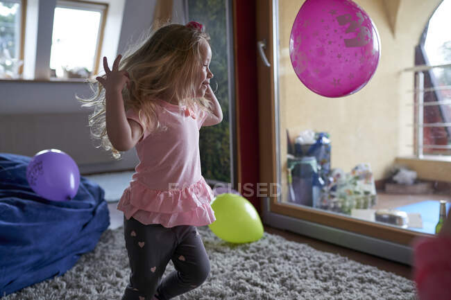 Glückliches kleines Mädchen läuft nach Hause und spielt mit Luftballons. — Stockfoto