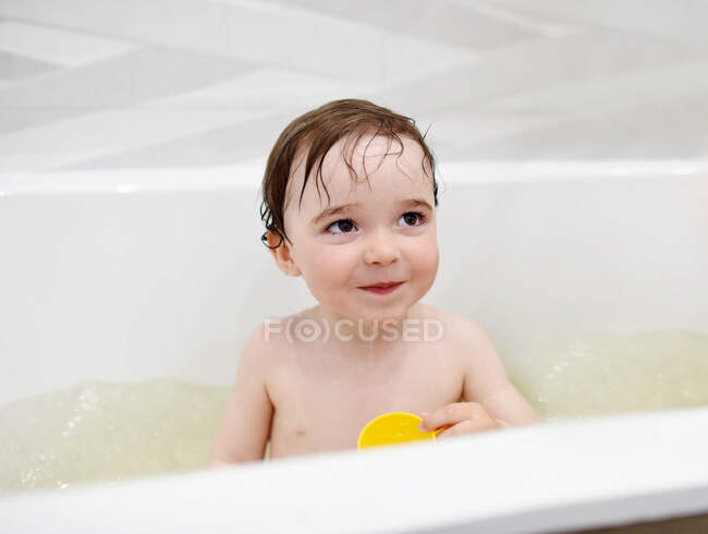 Adorable niño divirtiéndose durante la hora del baño por la noche - foto de stock