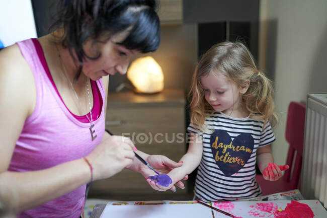 Cute little girl with teacher  painting in kindergarden — Stock Photo