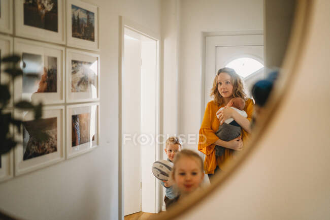 Blanco mamá y niños caminando a través de la puerta en casa - foto de stock