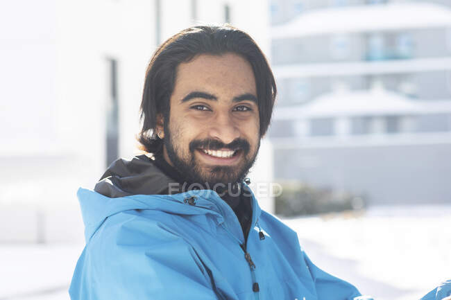 Young man standing outside in snow with long hair — Stock Photo