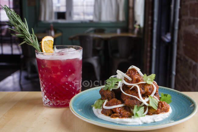 A colorful plate of fried cauliflower sits on table with pink cocktail — Stock Photo