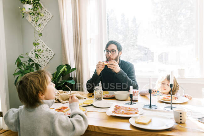 Семья завтракает вместе за обеденным столом в их доме — стоковое фото