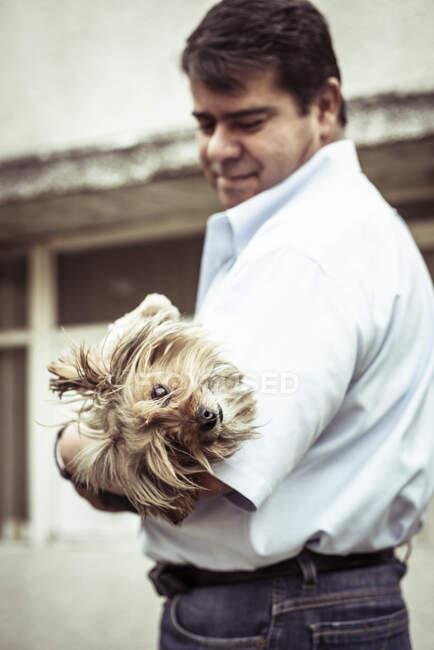 Homme tenant chien chiot gommage mignon regardant la caméra — Photo de stock