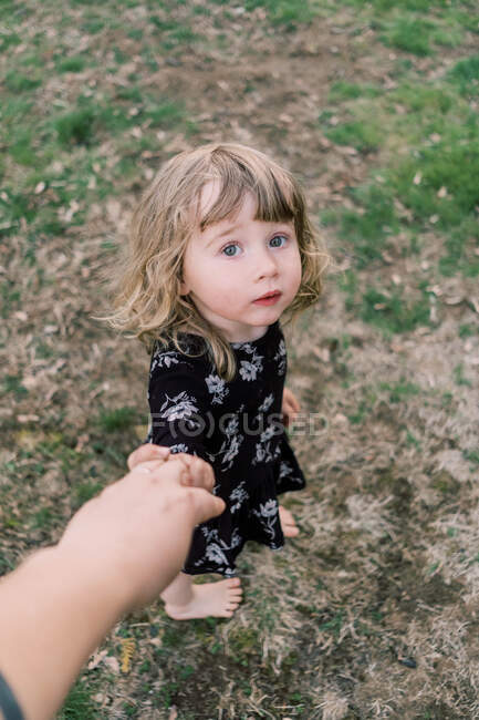 Маленькая босоногая девочка держит за руку свою мать, смотрит в глаза — стоковое фото