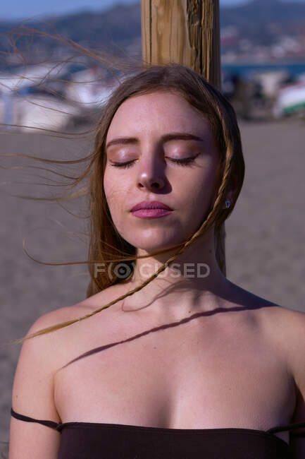 Головной портрет девушки глаза закрыты солнцем на пляже — стоковое фото