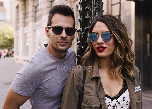 Couple of boyfriend and girlfriend wearing sunglasses on a city — Stock Photo