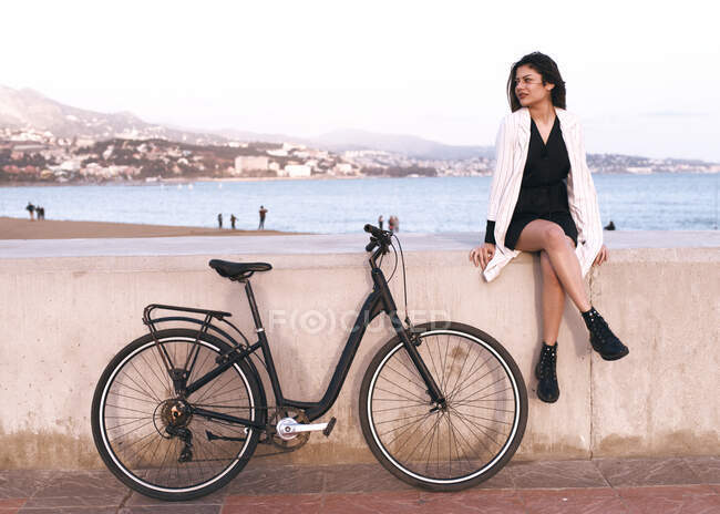 Jolie jeune femme avec ses promenades à vélo le long du port — Photo de stock