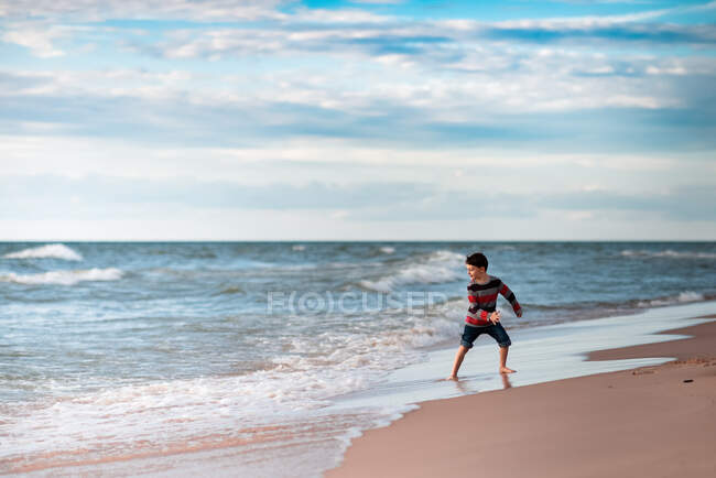 Chico en el lago Michigan divertirse en el agua en la playa - foto de stock