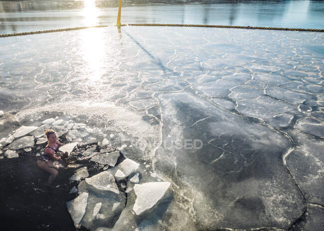 Mulher segurando gelo sólido enquanto flutua no oceano congelado na Dinamarca — Fotografia de Stock