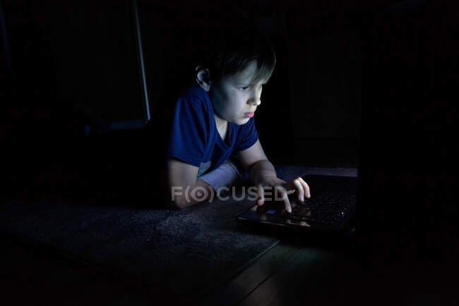 Boy sittingand usando um laptop, olhando para a tela do computador — Fotografia de Stock