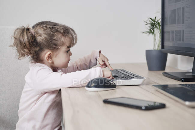 Une fille de 2 ans utilise un clavier d'ordinateur — Photo de stock