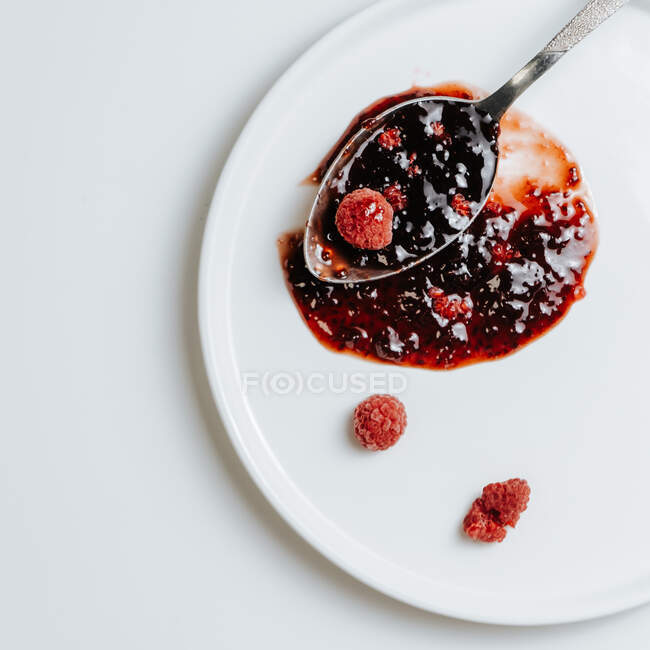Плямка малинового варення на білій тарілці з замороженими ягодами. — стокове фото