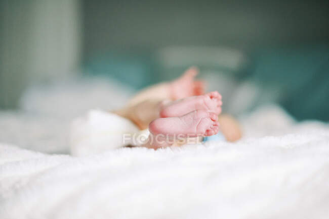 Vista de la parte inferior de los pies recién nacidos mientras el bebé se acuesta en la cama - foto de stock