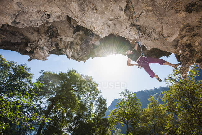 Donna matura che si arrampica sulla scogliera calcarea strapiombante in Laos — Foto stock