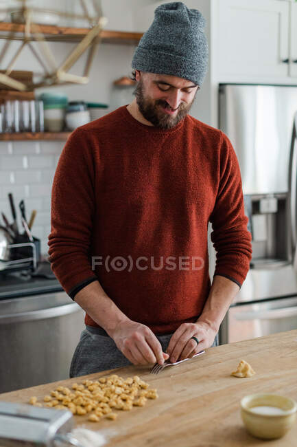 Feliz chef haciendo pasta en su acogedora cocina de bloque carnicero. - foto de stock