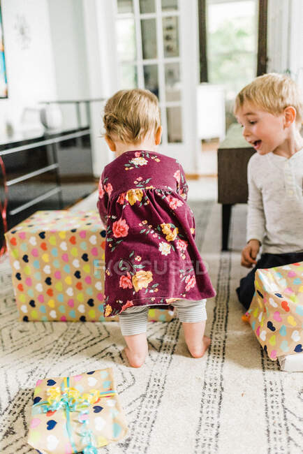 Kinder packen Geburtstagsgeschenke im Wohnzimmer aus und freuen sich — Stockfoto