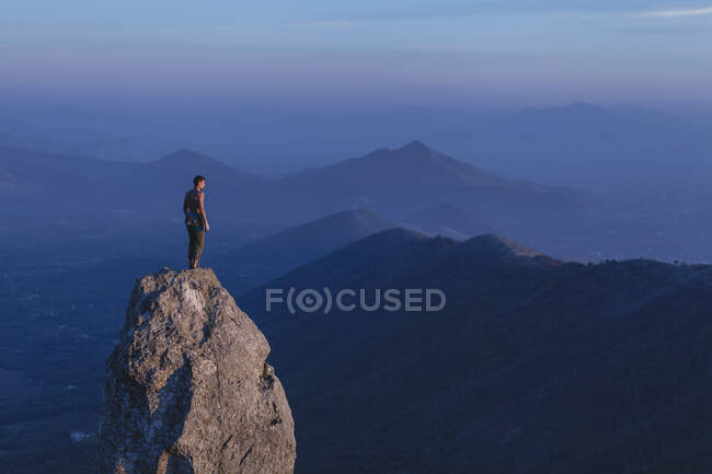 Grimpeur se tient sur un sommet en regardant le paysage — Photo de stock