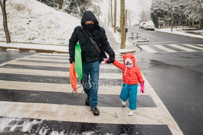 Papá y el niño cruzando la calle durante la tormenta de nieve - foto de stock