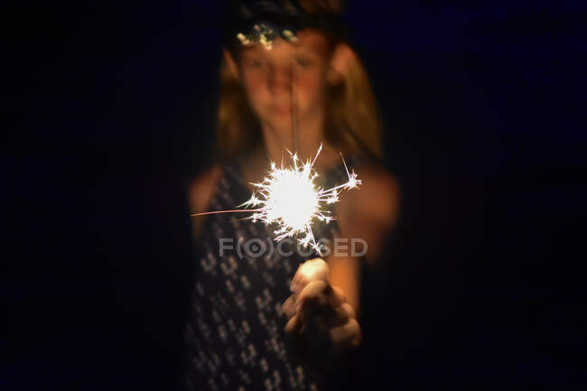 Girl holding a bright sparkler in her hand — Stock Photo