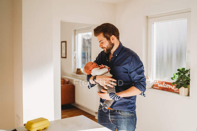 Щасливий тато тримає свою новонароджену дитину вдома під час карантину — стокове фото