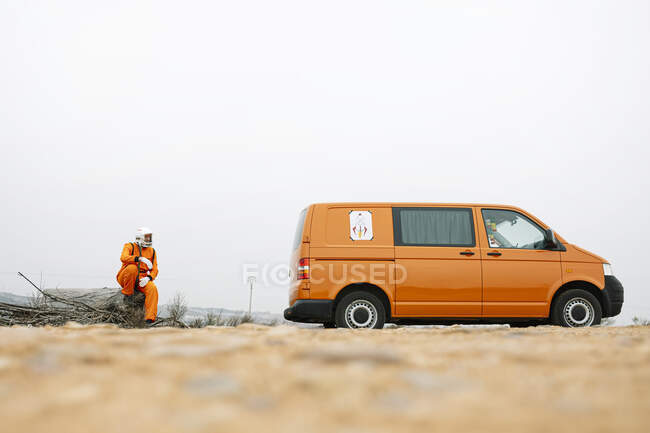Man dressed as an astronaut sitting next to the van — Stock Photo