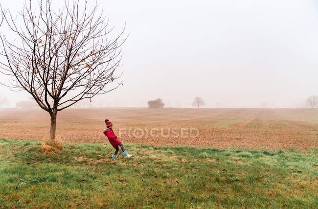 Little girl with read coat on a foggy morning in england countryside — Stock Photo